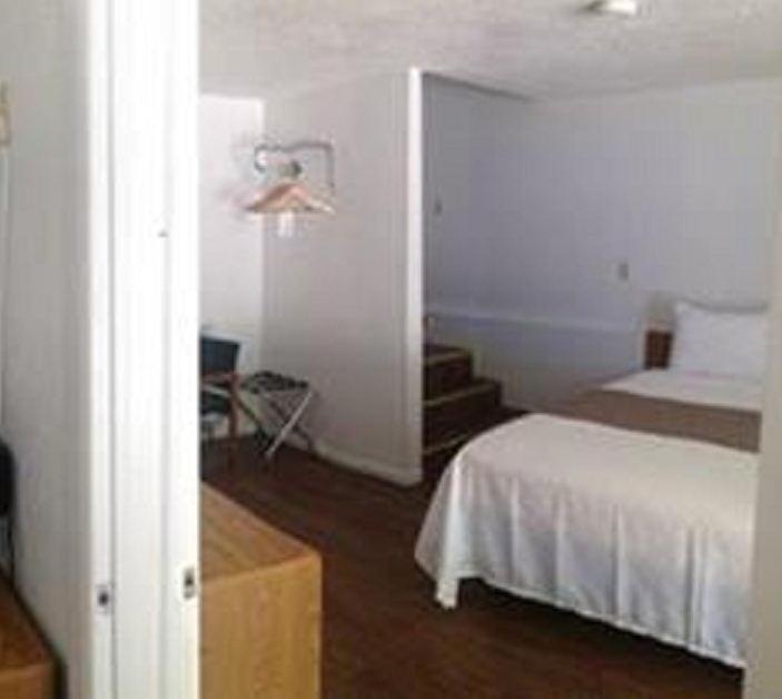 a bedroom with a bed and a room with a staircase at The Brookside Motel / Mt. Rushmore in Keystone