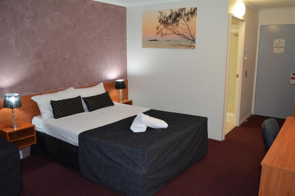una camera d'albergo con un letto e un asciugamano sopra di Hampton Villa Motel a Rockhampton