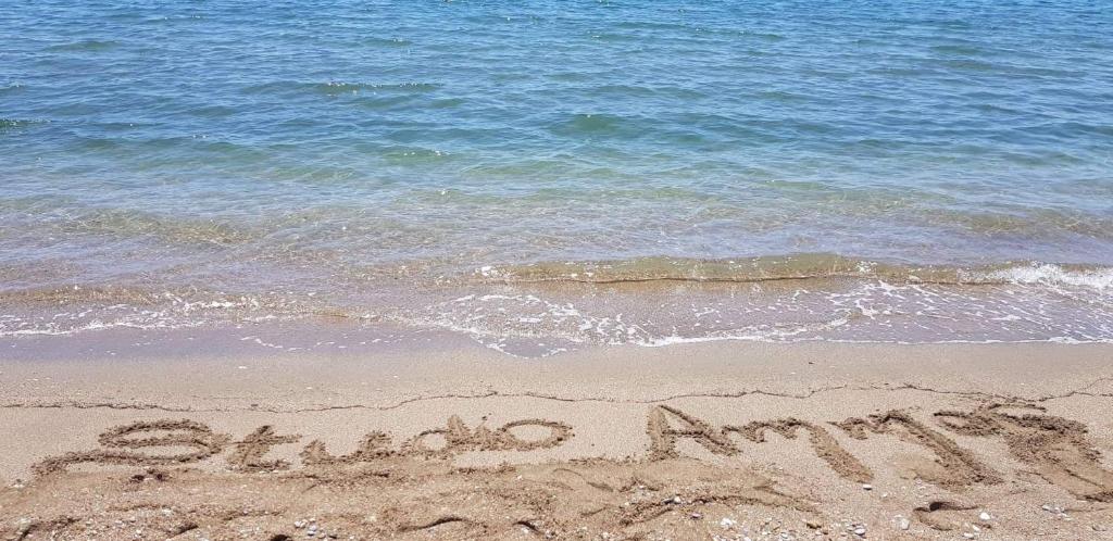 a word written in the sand on the beach at Ammos Apartments in Néa Karváli