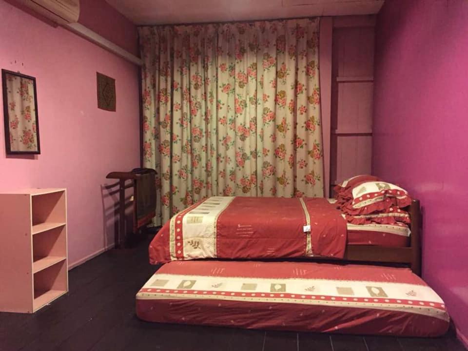 2 Einzelbetten in einem Zimmer mit rosa Wänden in der Unterkunft trisya homestay in Kuala Terengganu