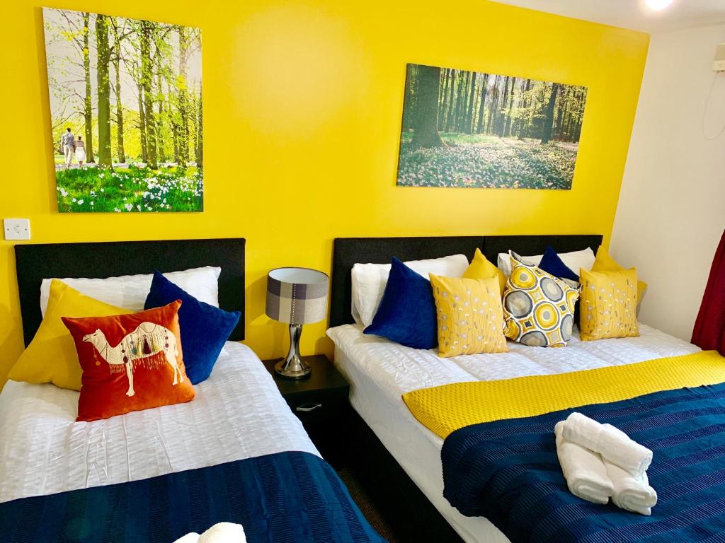 2 łóżka w pokoju z żółtymi ścianami w obiekcie 2 Bedrooms Modern Apartment, Lounge, Full Kitchen, Balcony, 5 minutes Stratford Station w Londynie