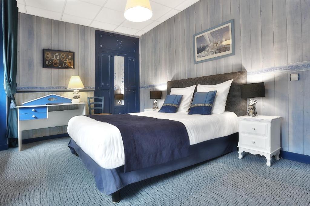 - une grande chambre avec un grand lit aux murs bleus dans l'établissement Logis Hôtel-Restaurant Les Voyageurs, à La Coquille