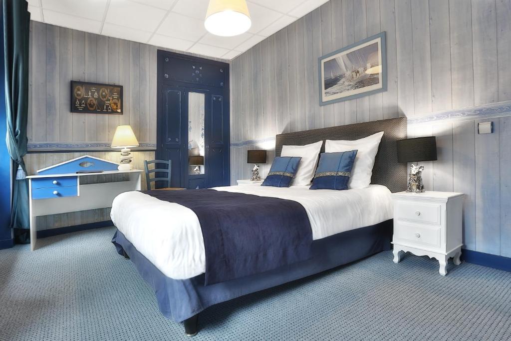 een grote slaapkamer met een groot bed met blauwe muren bij Logis Hôtel-Restaurant Les Voyageurs in La Coquille