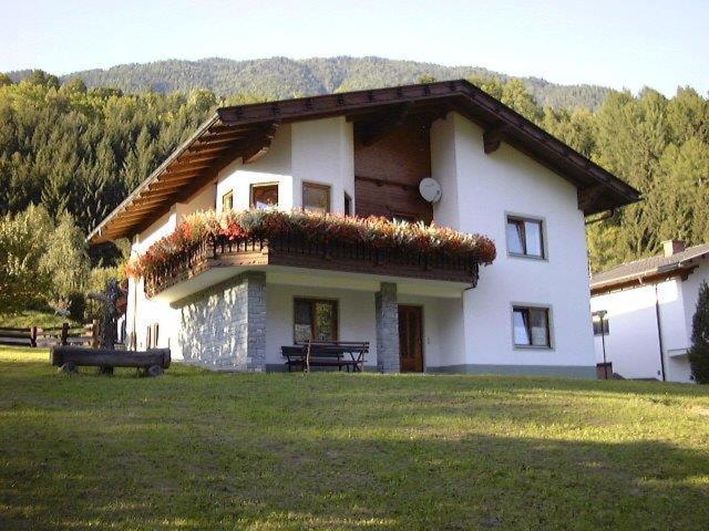 a large white house with a bench in front of it at Ferienwohnung Ebner in Flattach