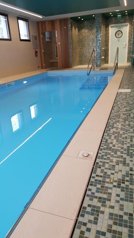 a swimming pool with blue water and a tile floor at Domitys - Les Robes d'Airain in Caen