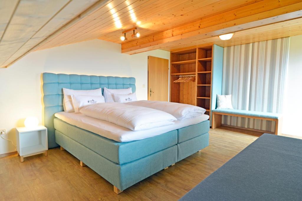 Schlafzimmer mit einem großen Bett mit blauem Kopfteil in der Unterkunft Pleschinhof in Velden am Wörthersee