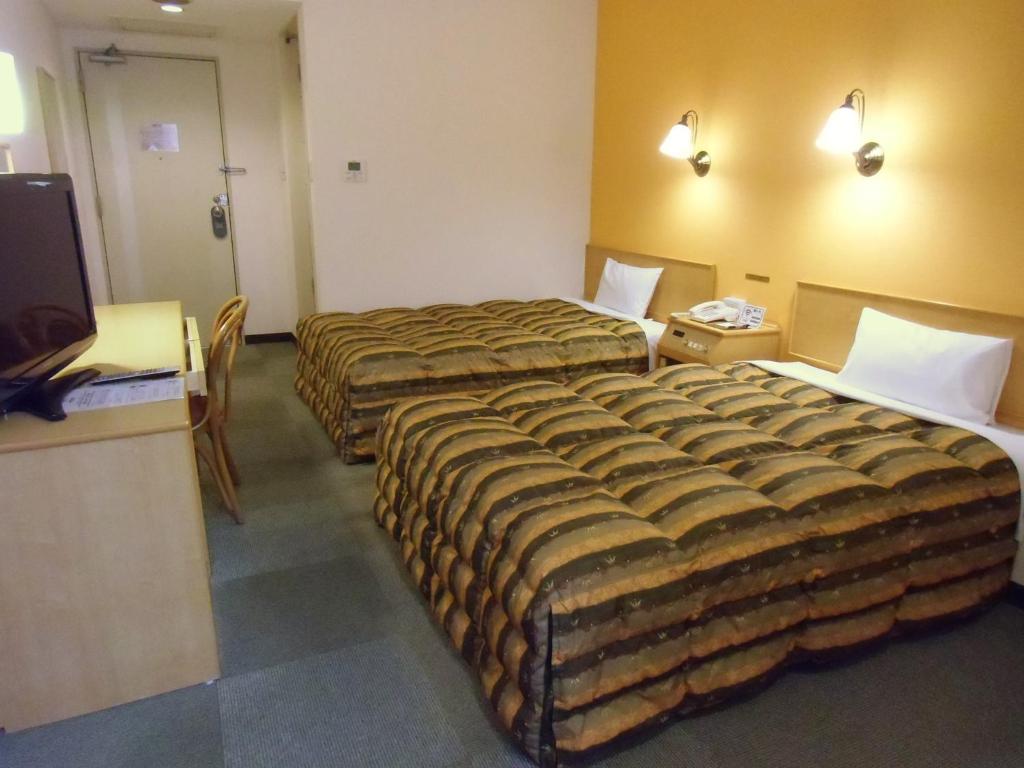 a hotel room with two beds and a flat screen tv at Hotel Oaks Early-Bird Osaka Morinomiya/ Vacation STAY 28791 in Osaka