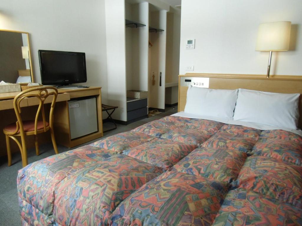 a bedroom with a bed and a desk with a television at Hotel Oaks Early-Bird Osaka Morinomiya/ Vacation STAY 28787 in Osaka