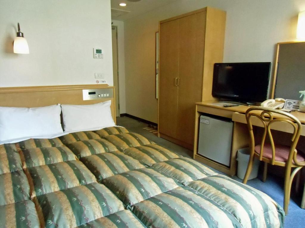 a hotel room with a bed and a desk and a television at Hotel Oaks Early-Bird Osaka Morinomiya/ Vacation STAY 28691 in Osaka