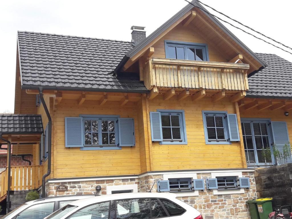 a yellow house with a balcony on top of it at Alpine Cottage in Bled