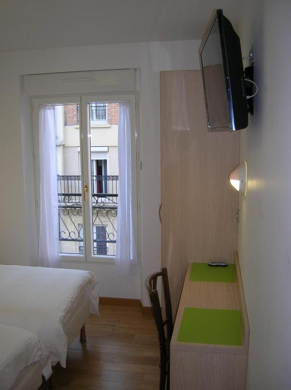 a bedroom with a bed and a desk and a window at Hotel Darcet in Paris