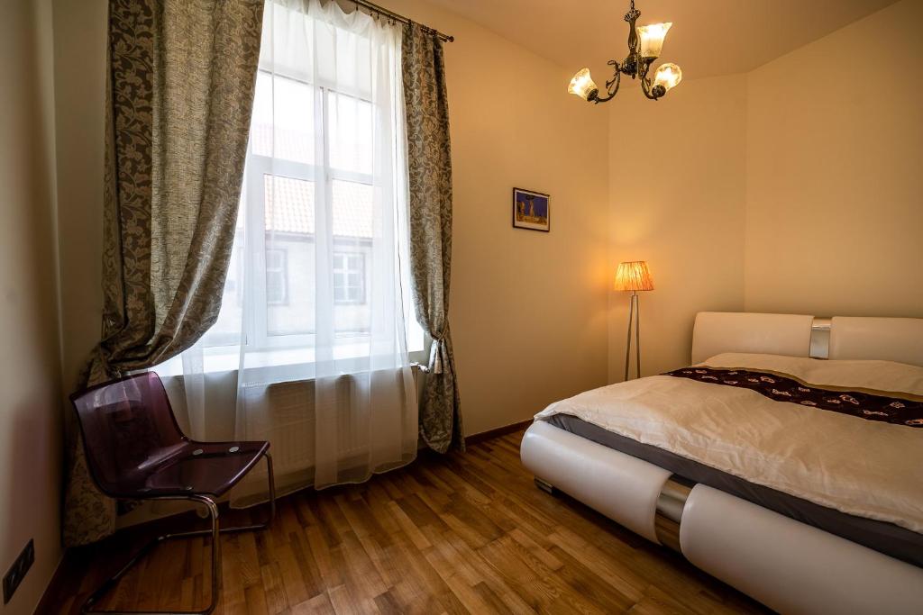 Un dormitorio con una cama y una ventana con una silla. en Concert Hall, en Liepāja