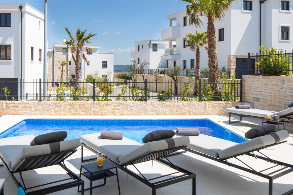 a pool with chaise lounge chairs and a swimming pool at Luxury Apartment La Mer in Murter
