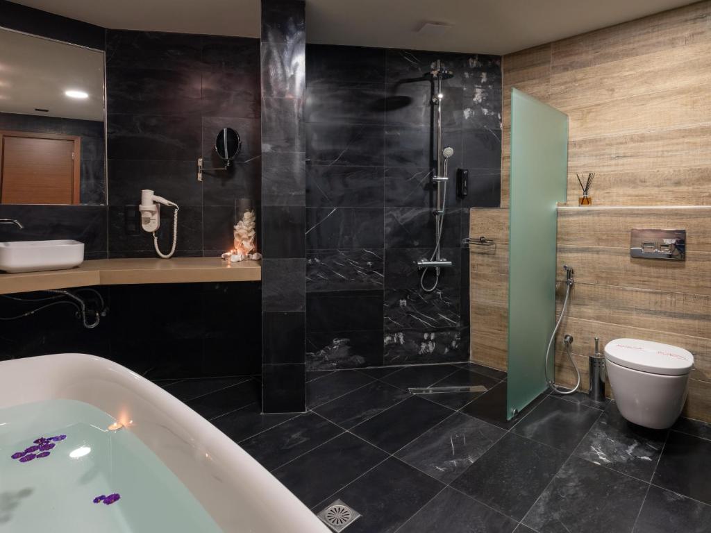 a bathroom with a tub and a toilet and a shower at Eva Mare Hotel & Suites - Adults only in Agia Pelagia