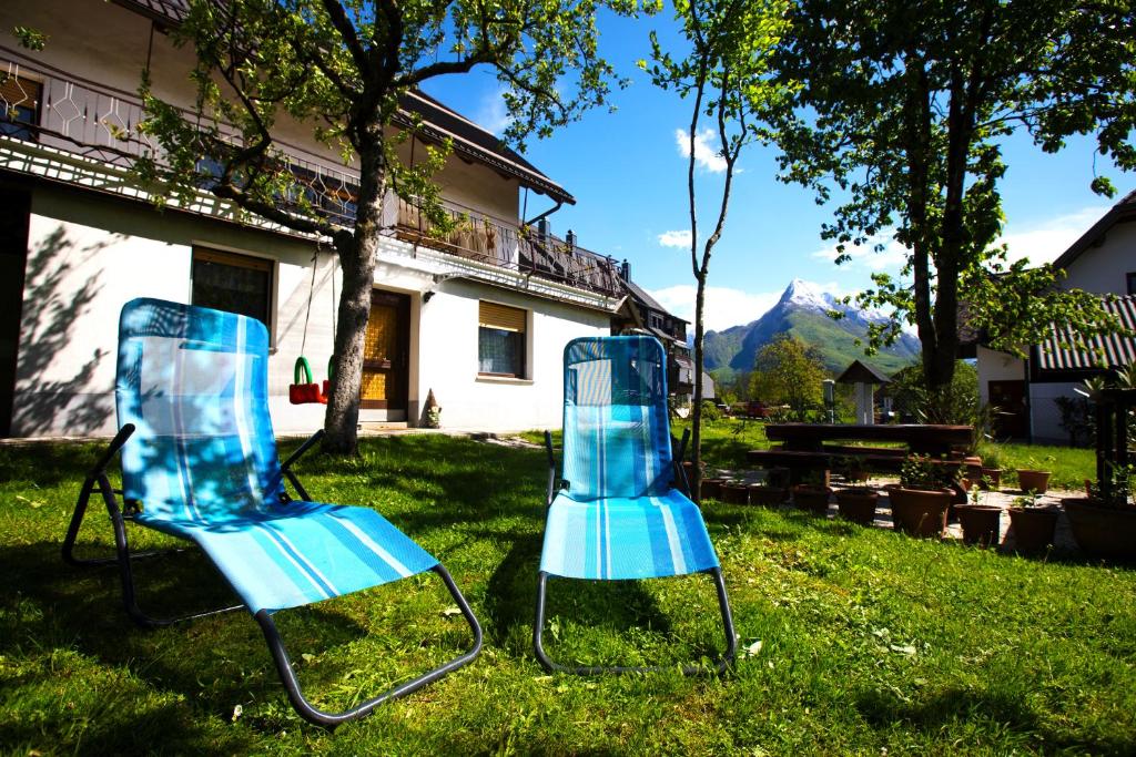 deux chaises bleues assises dans l'herbe devant une maison dans l'établissement Bovec Holiday House, à Bovec