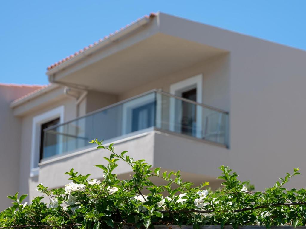a white house with a glass balcony on it at Eva Mare Hotel & Suites - Adults only in Agia Pelagia