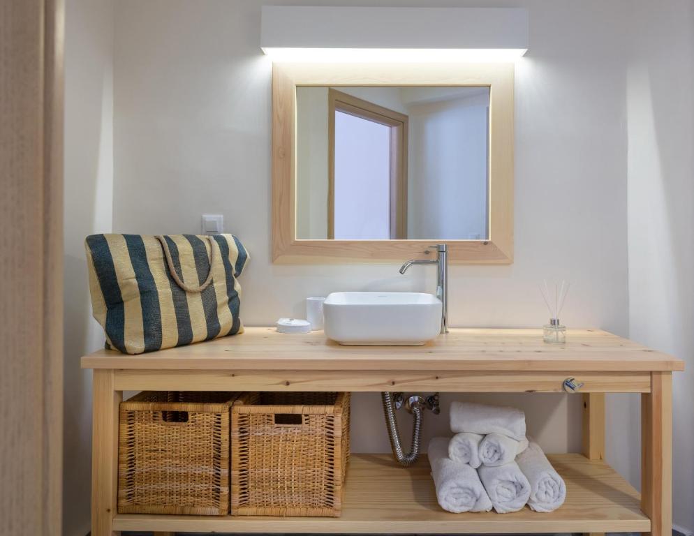 a bathroom with a sink and a mirror and towels at Eva Mare Hotel & Suites - Adults only in Agia Pelagia
