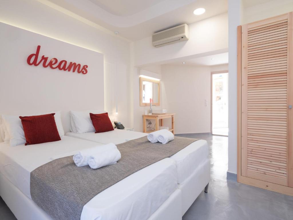 a white bedroom with two beds with towels on them at Eva Mare Hotel & Suites - Adults only in Agia Pelagia