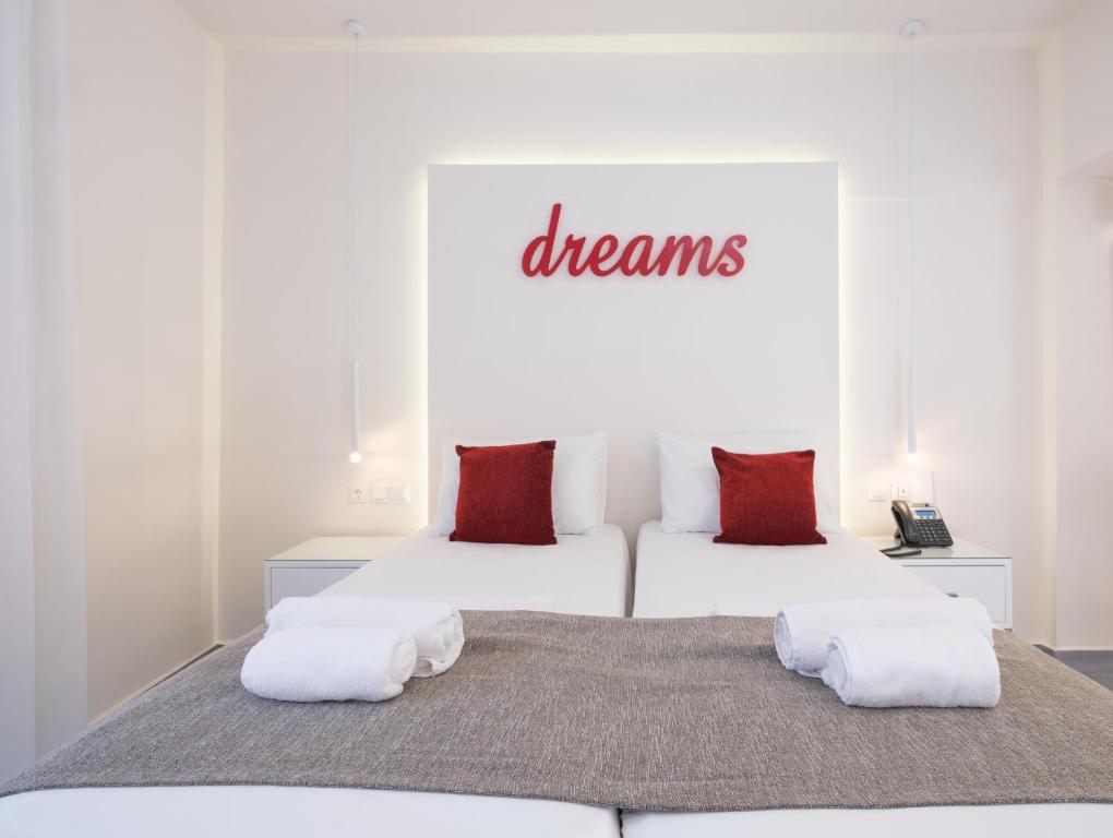 two beds in a white room with red pillows at Eva Mare Hotel & Suites - Adults only in Agia Pelagia