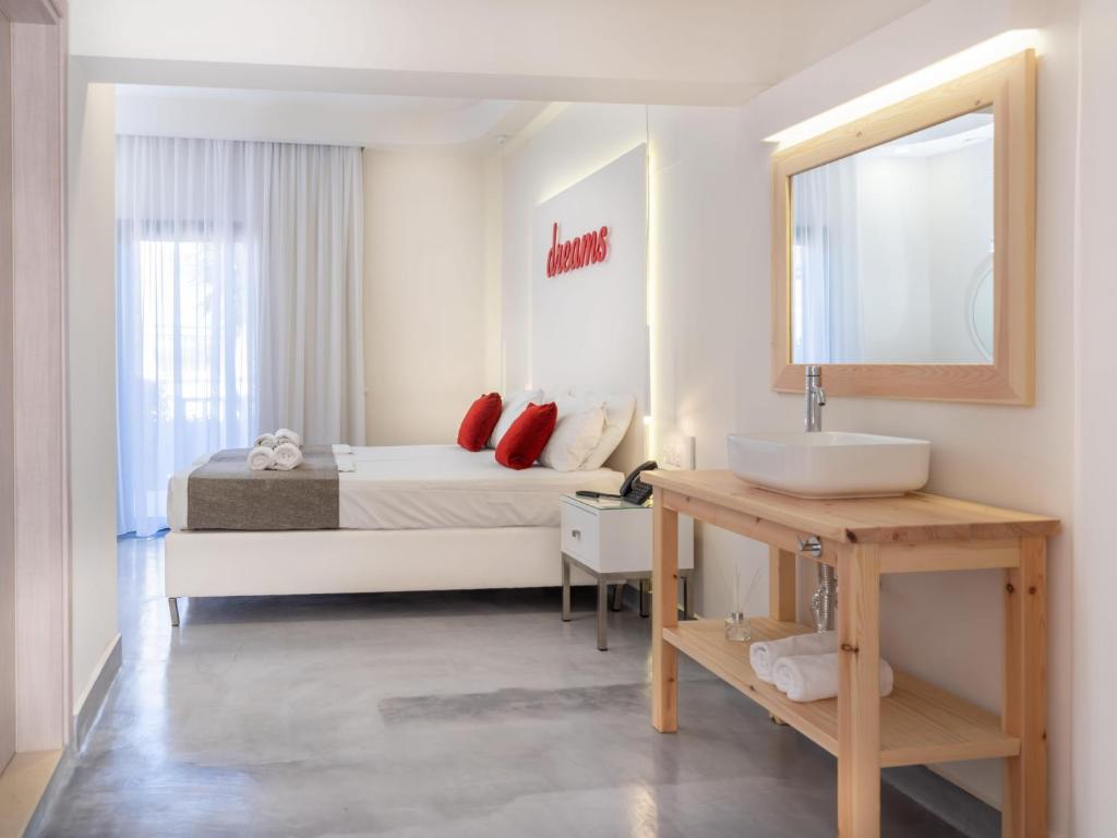 a bathroom with a bed with a sink and a mirror at Eva Mare Hotel & Suites - Adults only in Agia Pelagia