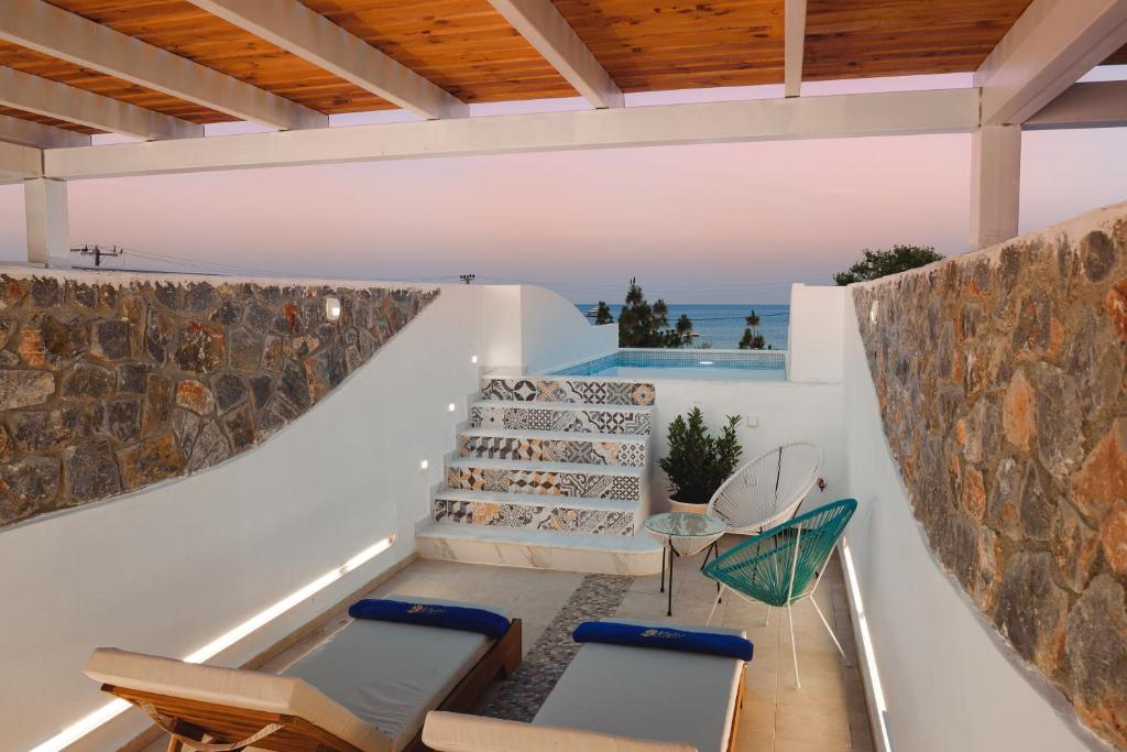 an outdoor patio with chairs and a stone wall at Mylos Luxury Escape in Faliraki