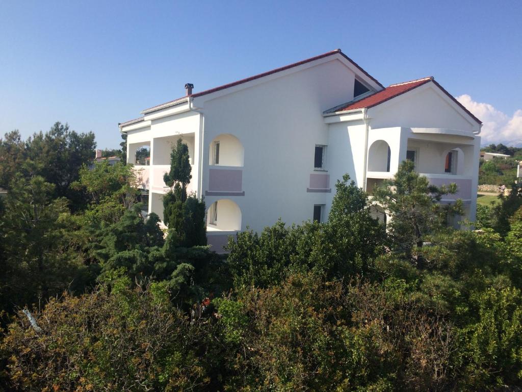 a white house on a hill with trees at Apartments MiaMaja in Novalja