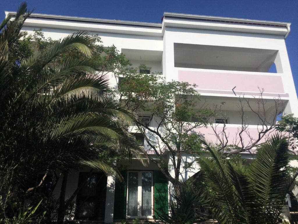a white building with palm trees in front of it at Apartments MiaMaja in Novalja