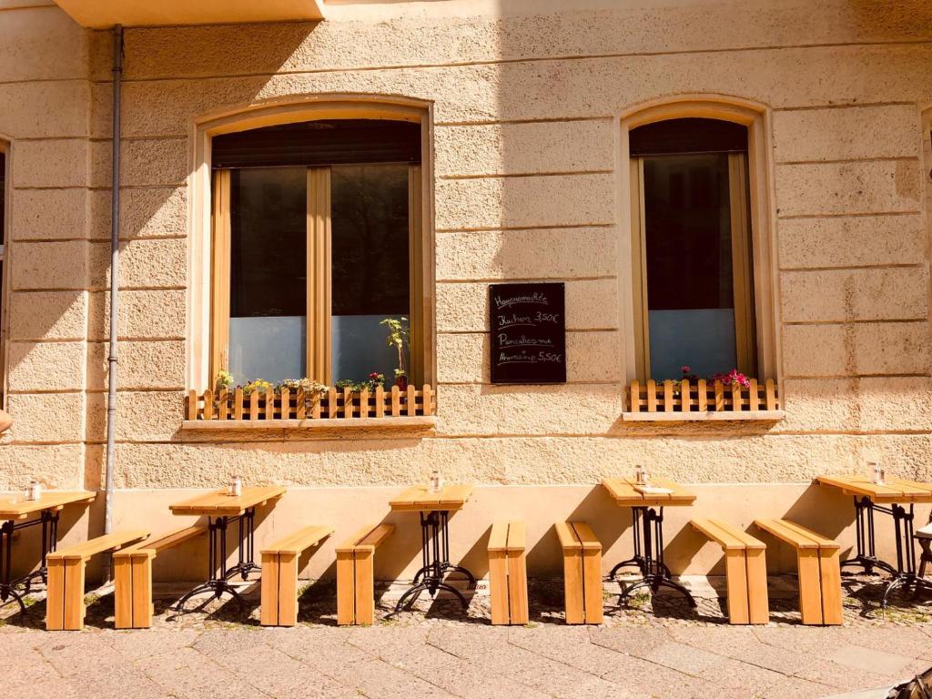 un groupe de tables et de bancs devant un bâtiment dans l'établissement Pension Kaffeefreunde, à Berlin