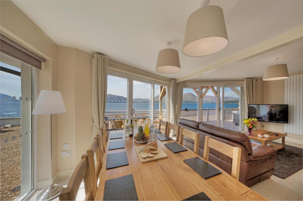 Beach Houses with Hot Tubs في غلينكو: غرفة معيشة مع طاولة طعام وإطلالة على المحيط