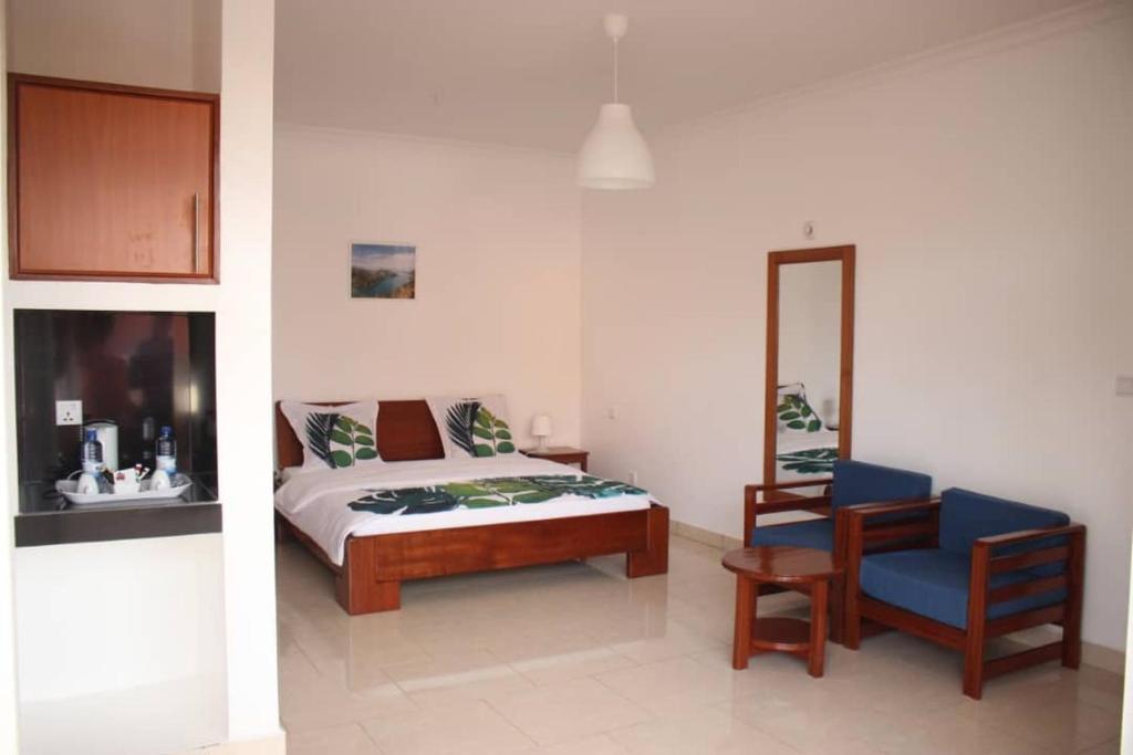 ein Schlafzimmer mit einem Bett, einem Stuhl und einem Spiegel in der Unterkunft Hôtel Maisons-Sifa in Butare