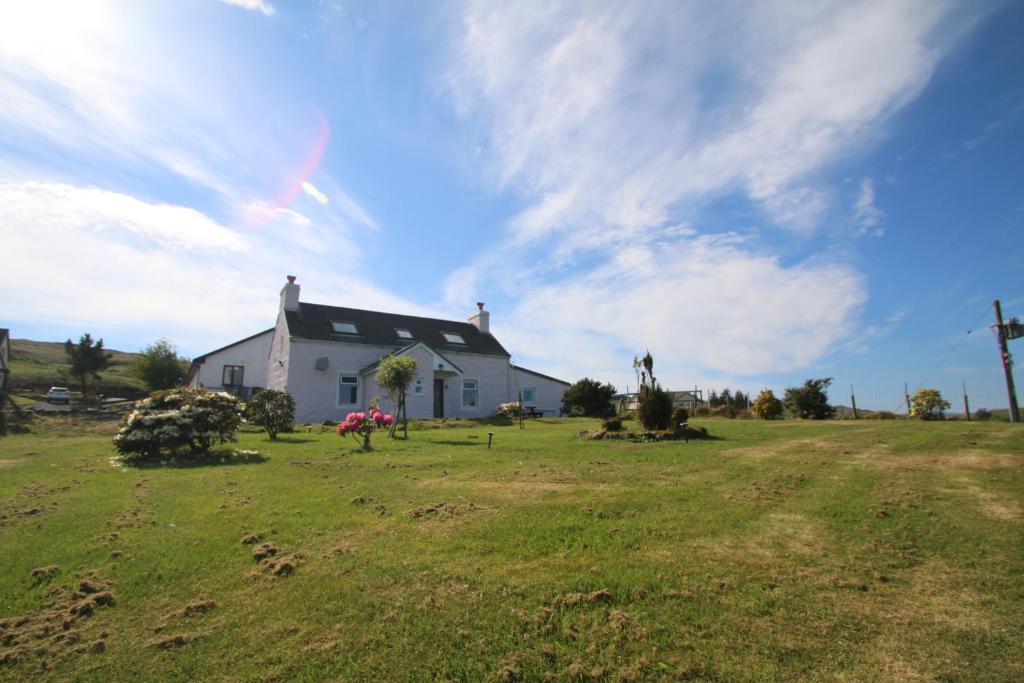 a white house on a field with a grass yard at Arle Farmhouse in Tobermory