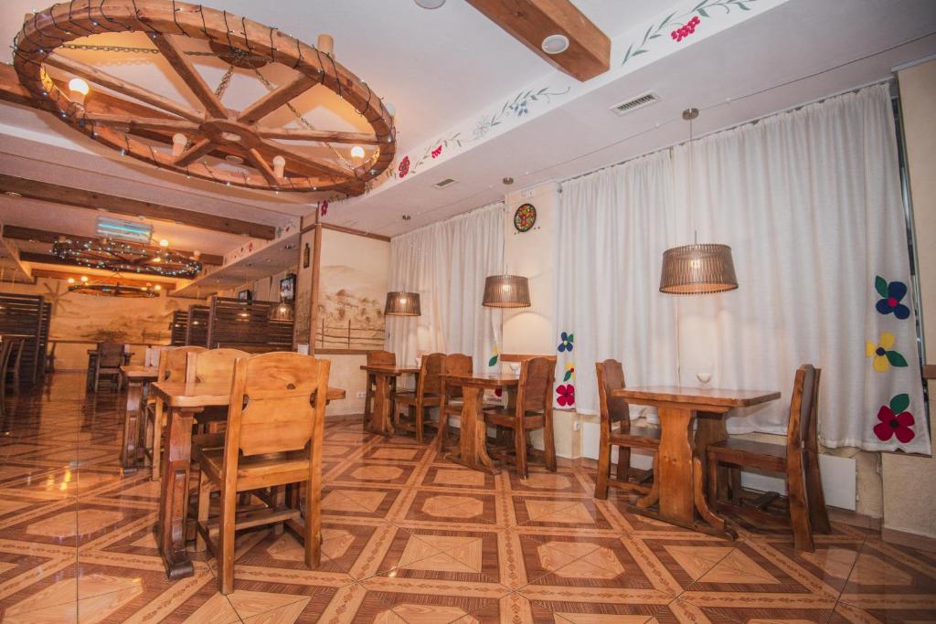 a restaurant with wooden tables and chairs and a chandelier at Autopapa in Rustavi