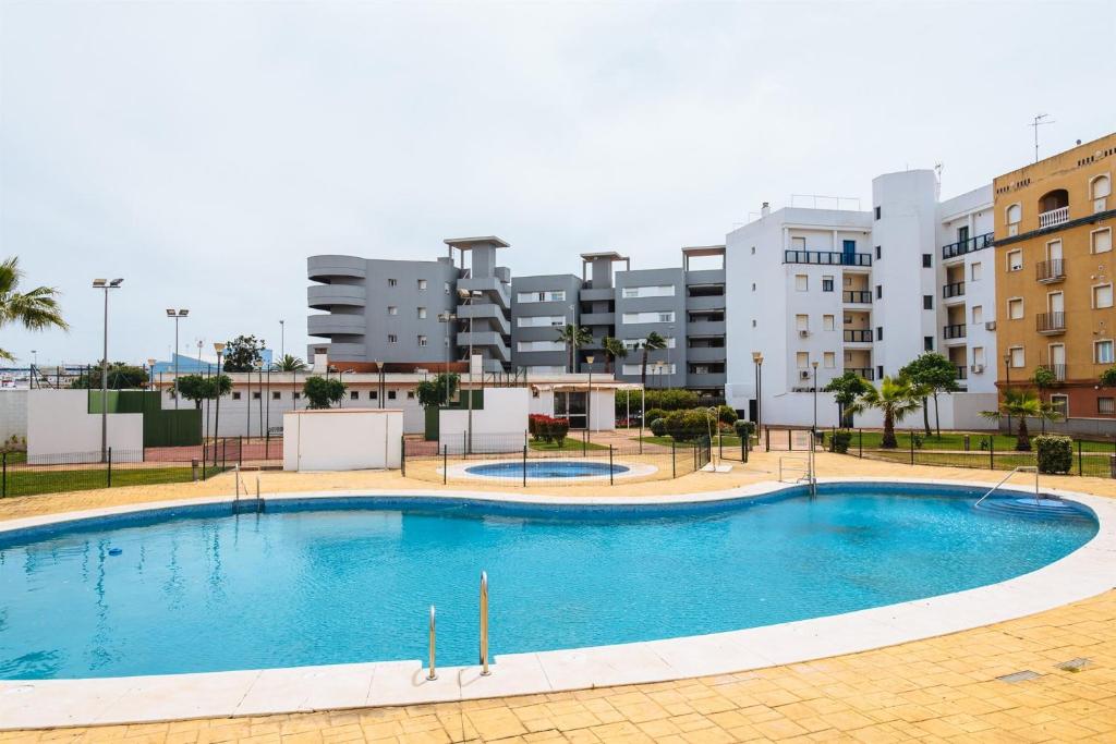 une grande piscine en face d'un bâtiment dans l'établissement Playa del Cantil, 3 bedrooms and 2 free parking, à Isla Cristina