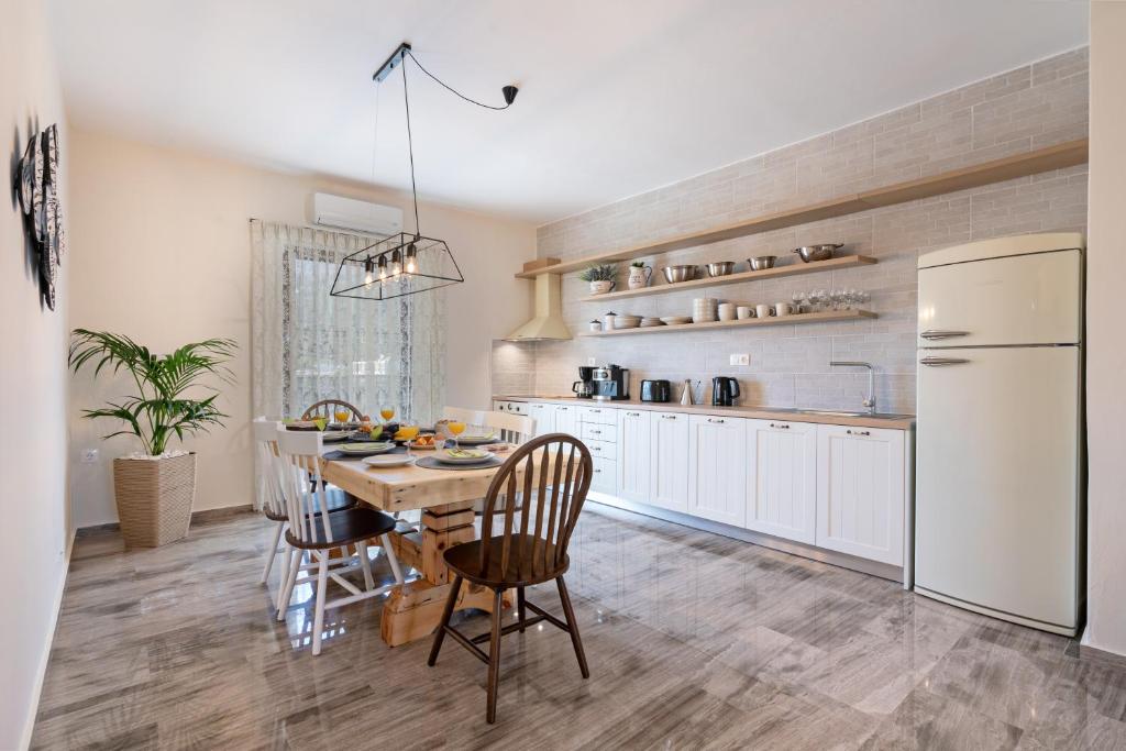 uma cozinha com uma mesa e cadeiras e um frigorífico branco em Plakias Family Apartment em Plakiás