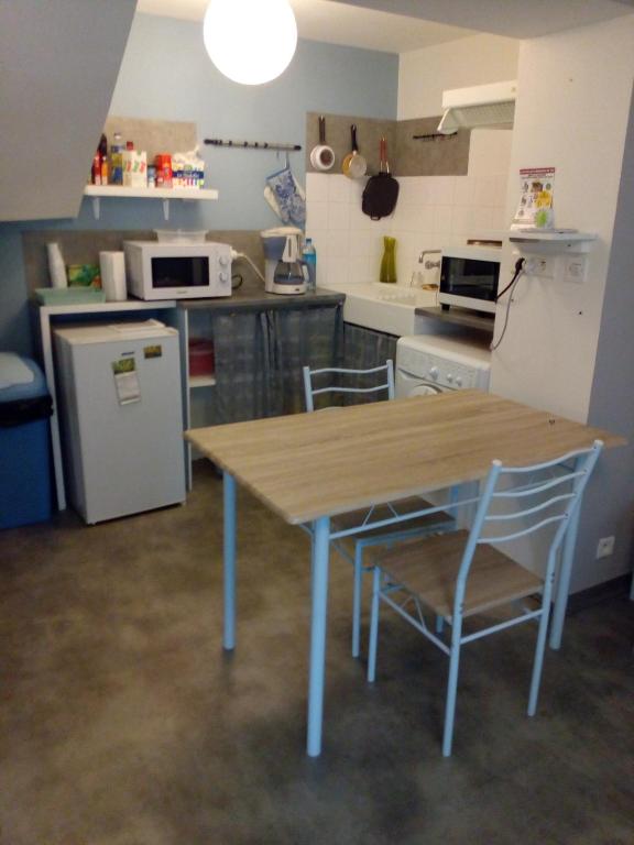 une cuisine avec une table en bois et deux chaises dans l'établissement La maison des remparts, à Lectoure