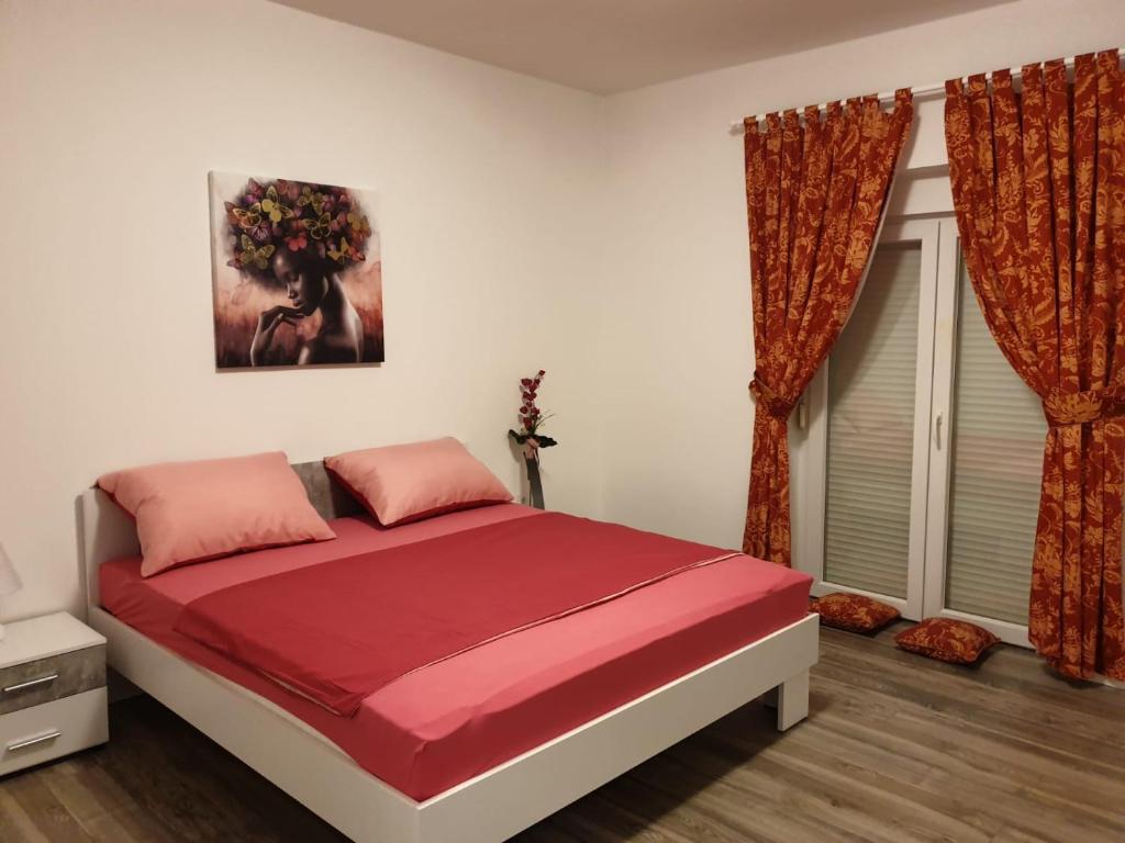 a bedroom with a large bed with red sheets and curtains at Dani in Zadar