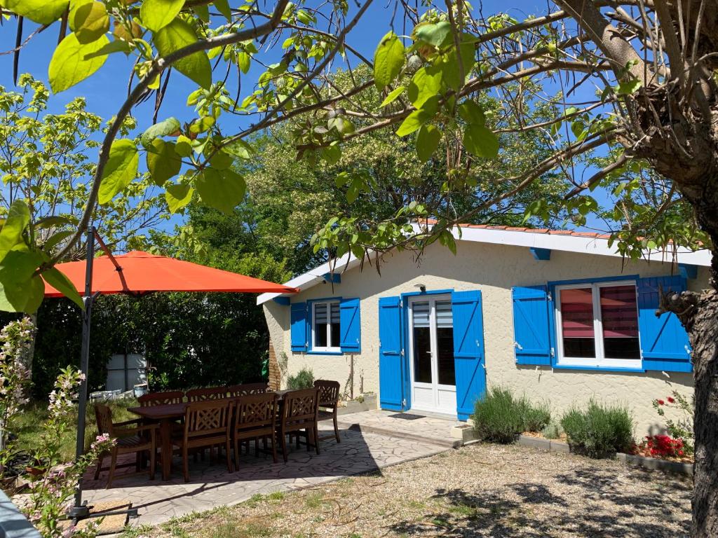 uma casa azul e branca com uma mesa e cadeiras em Lachanau Paradis em Hourtin