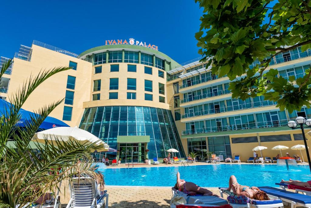 a hotel with people laying on lawn chairs in front of a swimming pool at Ivana Palace Hotel - Free Parking in Sunny Beach