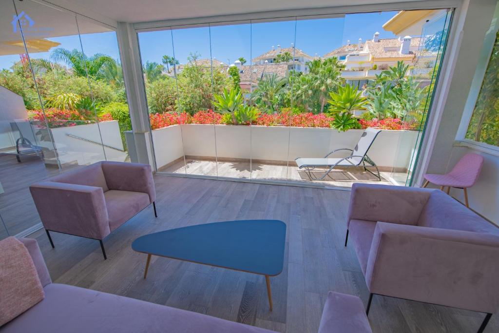 - un salon avec des chaises et une grande fenêtre dans l'établissement Luxury apartment at Lomas del Rey, Puente Romano, à Marbella