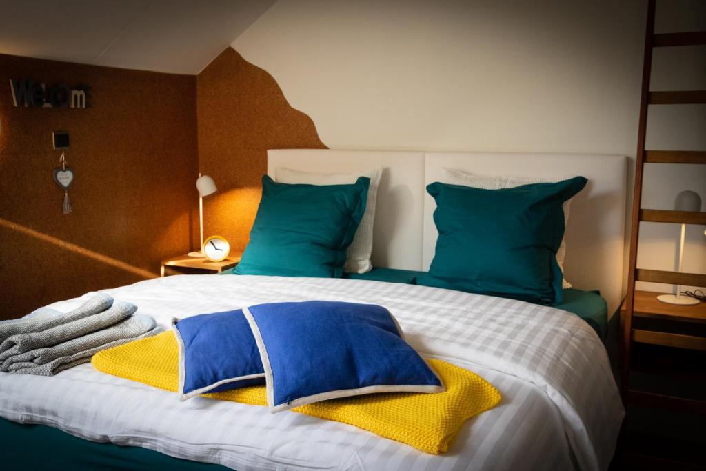 een slaapkamer met een groot bed met blauwe en groene kussens bij BC bed en comfort in Bilzen