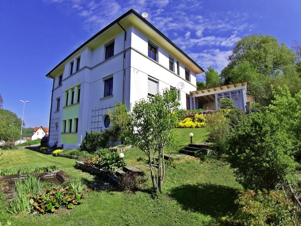 une maison blanche avec un jardin en face dans l'établissement Ferienwohnung Albstadt Panorama, à Albstadt