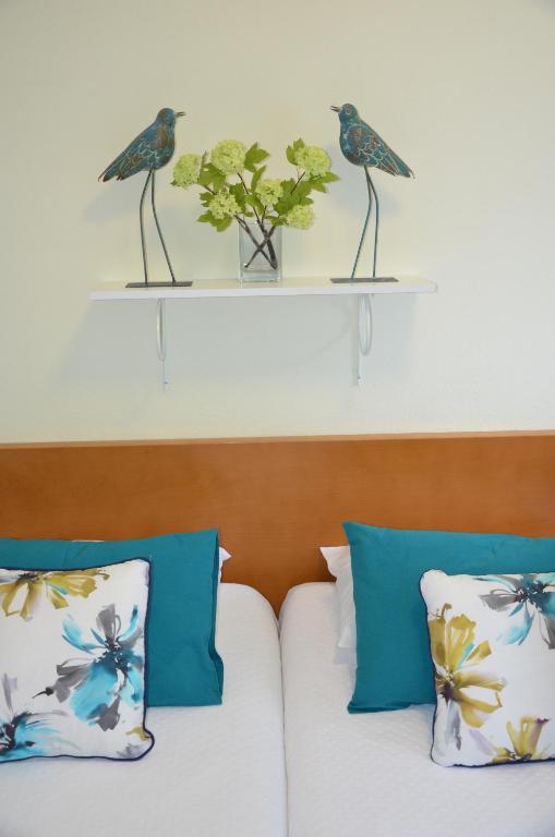 two birds on a shelf above a bed at ABLA Guest House in Carcavelos