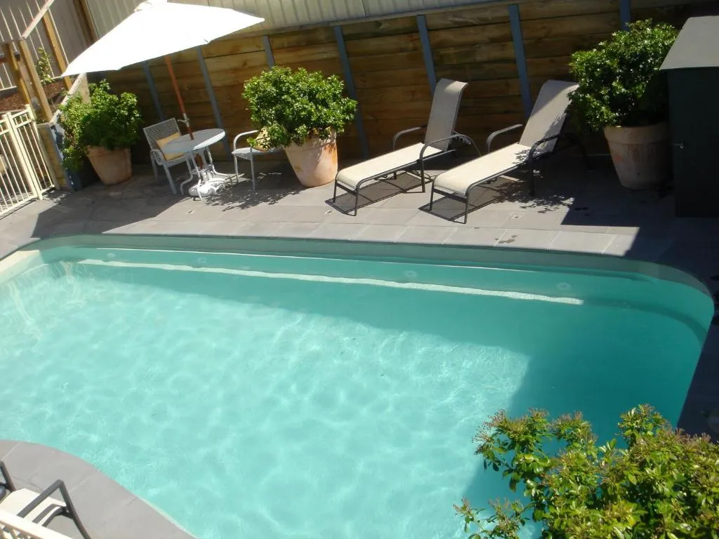 An outdoor pool with two sun lounges and a white umbrella