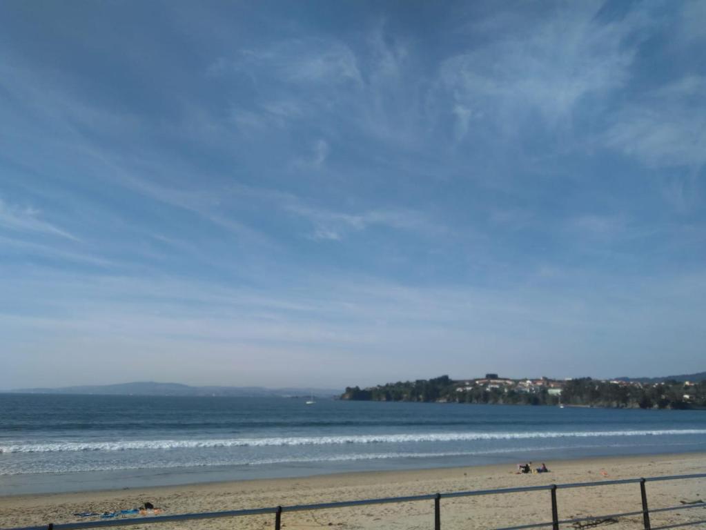 einen Strand mit einem Zaun und dem Meer in der Unterkunft Apartamento A pie de Playa in Miño