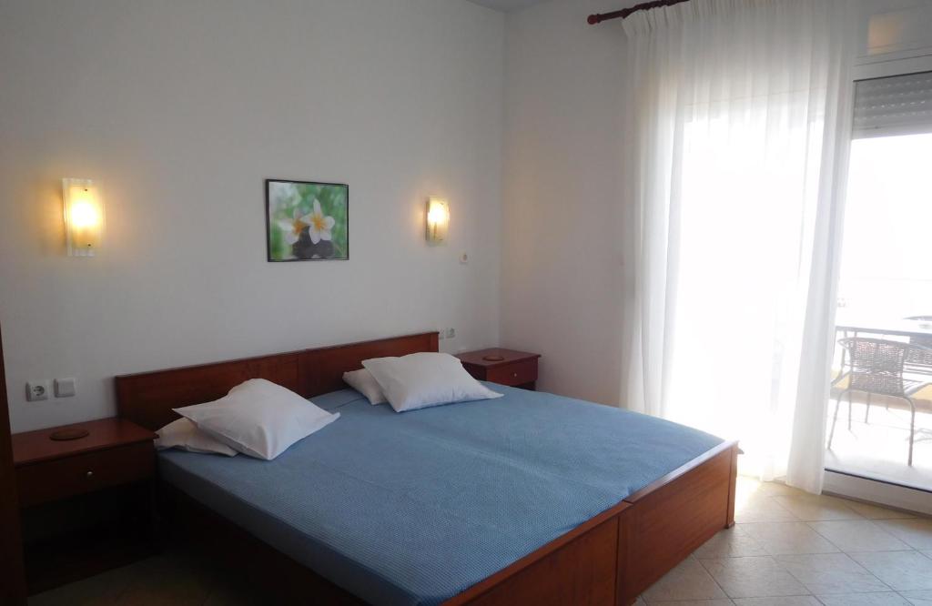 a bedroom with a bed with blue sheets and a window at Studios Stefania in Neos Marmaras