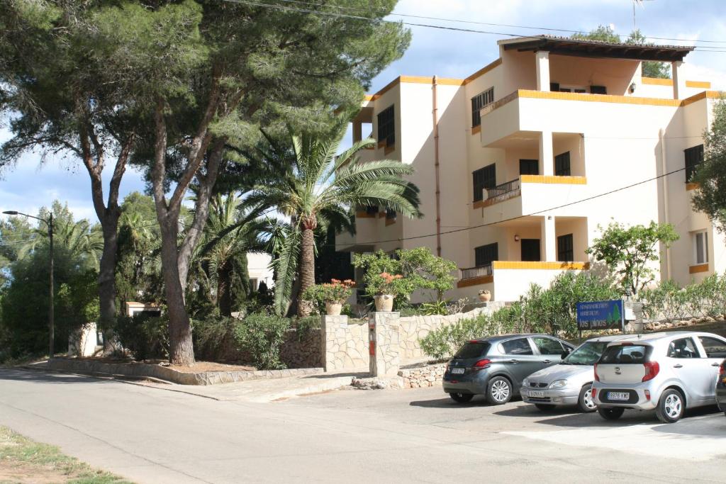 un estacionamiento con autos estacionados frente a un edificio en Apartamentos Los Pinos, en Cala Murada