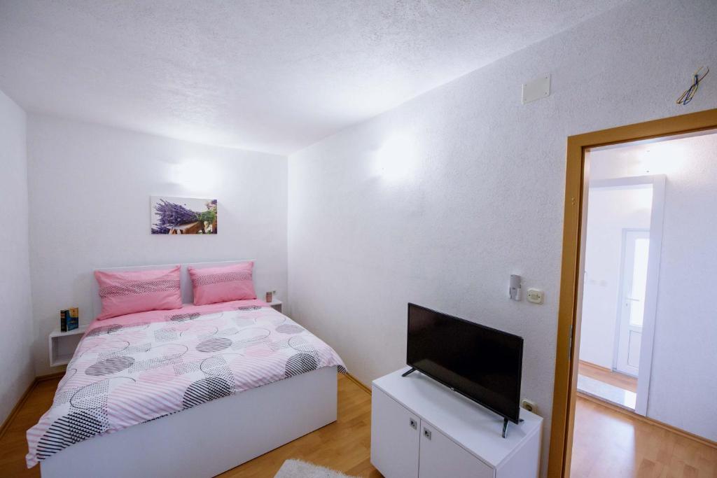 Schlafzimmer mit einem Bett und einem Flachbild-TV in der Unterkunft Apartman Sea view in Brist