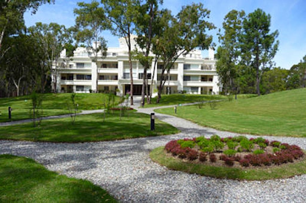 un gran edificio blanco con un jardín delante de él en Green Park - Lloret de Mar Punta del Este, en Punta del Este