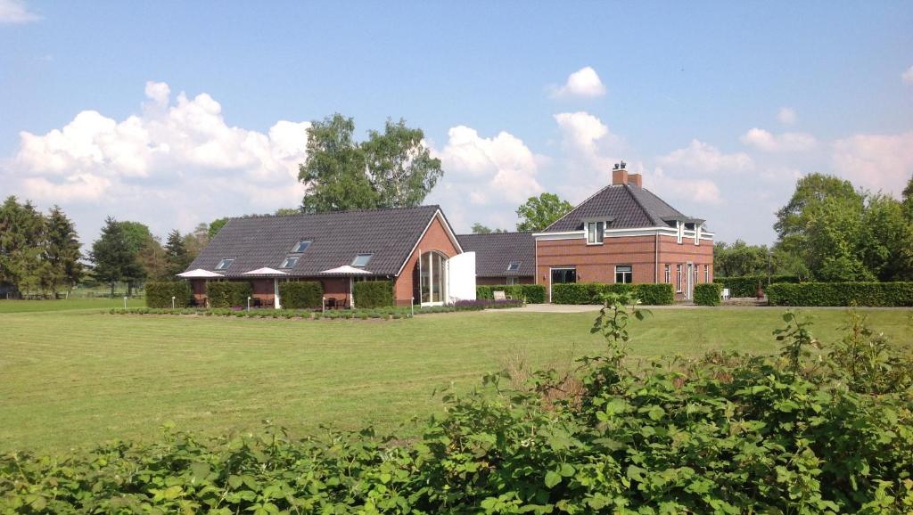 una casa grande con un gran campo delante en B&B De Veluwe Hoeve, en Eerbeek