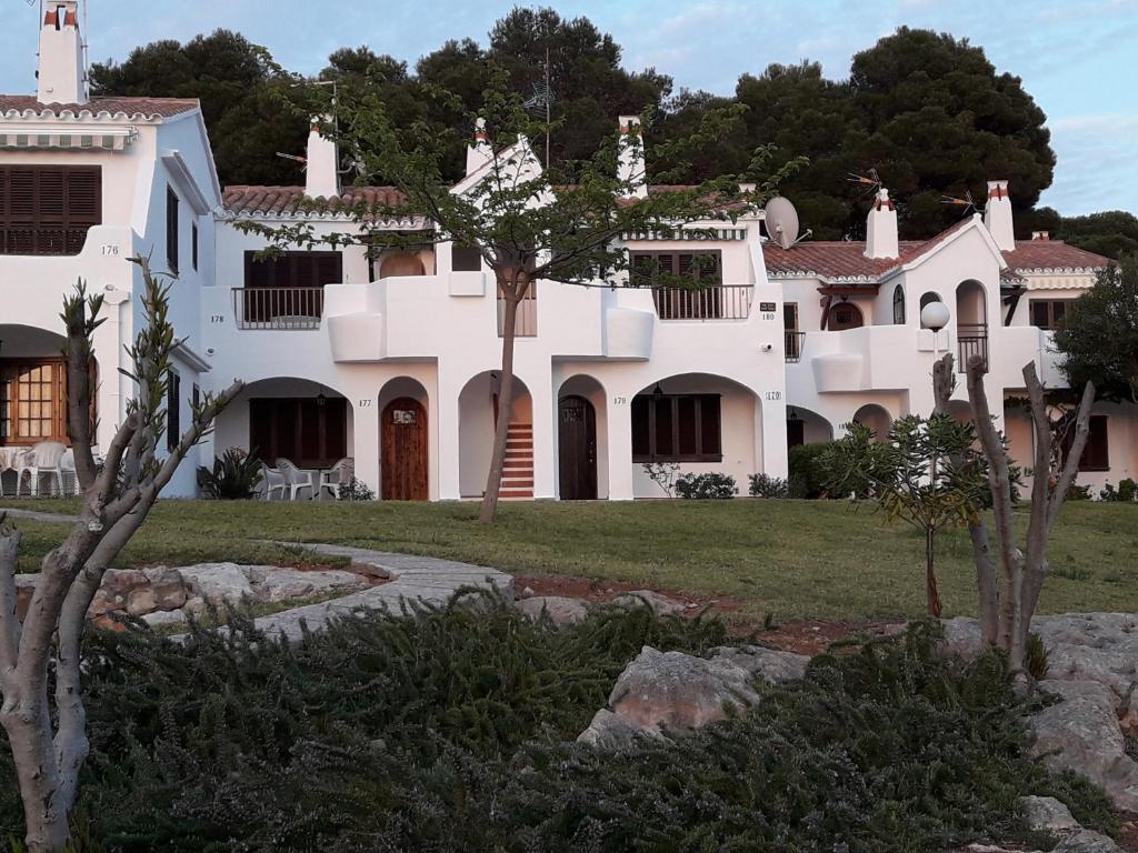 una grande casa bianca con alberi di fronte di CA NA ROSA Son Bou ad Alaior